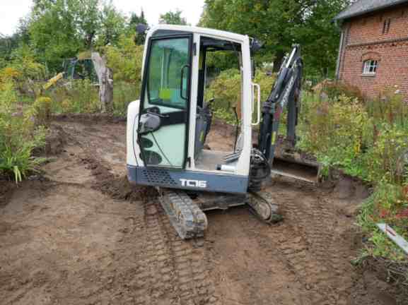 Bagger auf gebaggerter Gartenfläche.