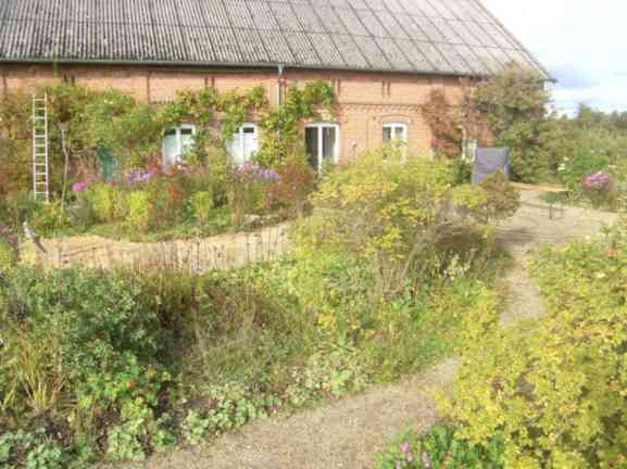 Südfassade Ziegelhaus, davor herbstlicher Garten mit Terrassenbereiche.
