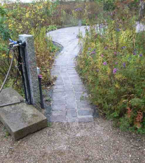 Schmaler Weg von Pflasterfläche in Übergang auf Malenter Deckschicht.