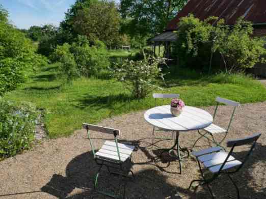 Terrasse mit weißen Gartenmöbeln und Wiese mit Rosen.